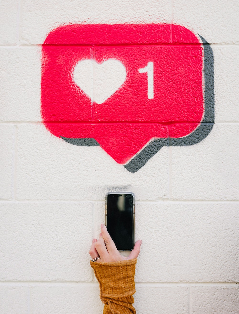 Wandmalerei mit einem sozialen Medium-Like und einer Hand, die ein Telefon hält.