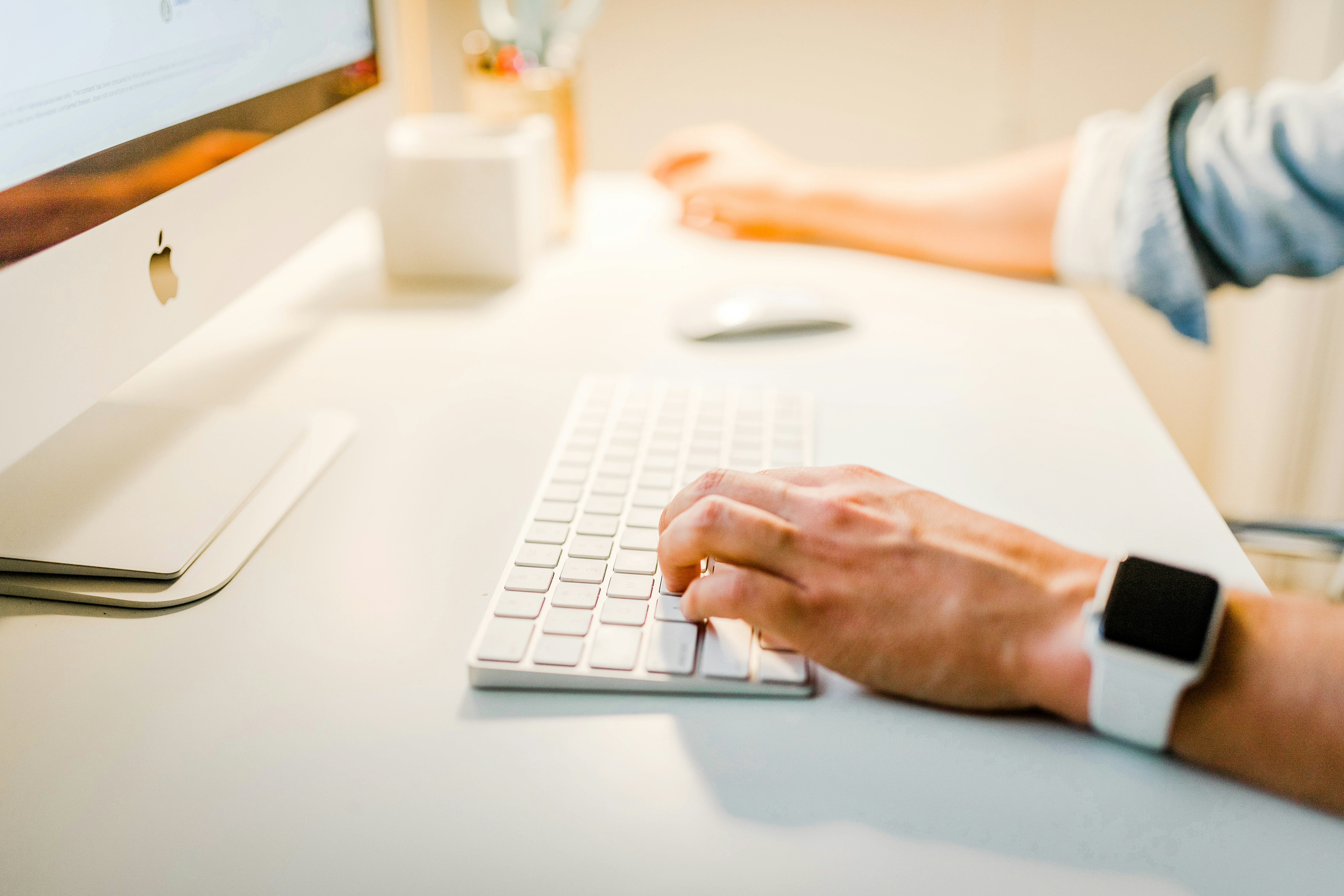 Person typing on a white keyboard at a desk